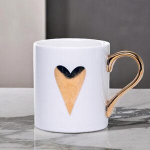 White ceramic mug adorned with a gold handle and a single golden heart